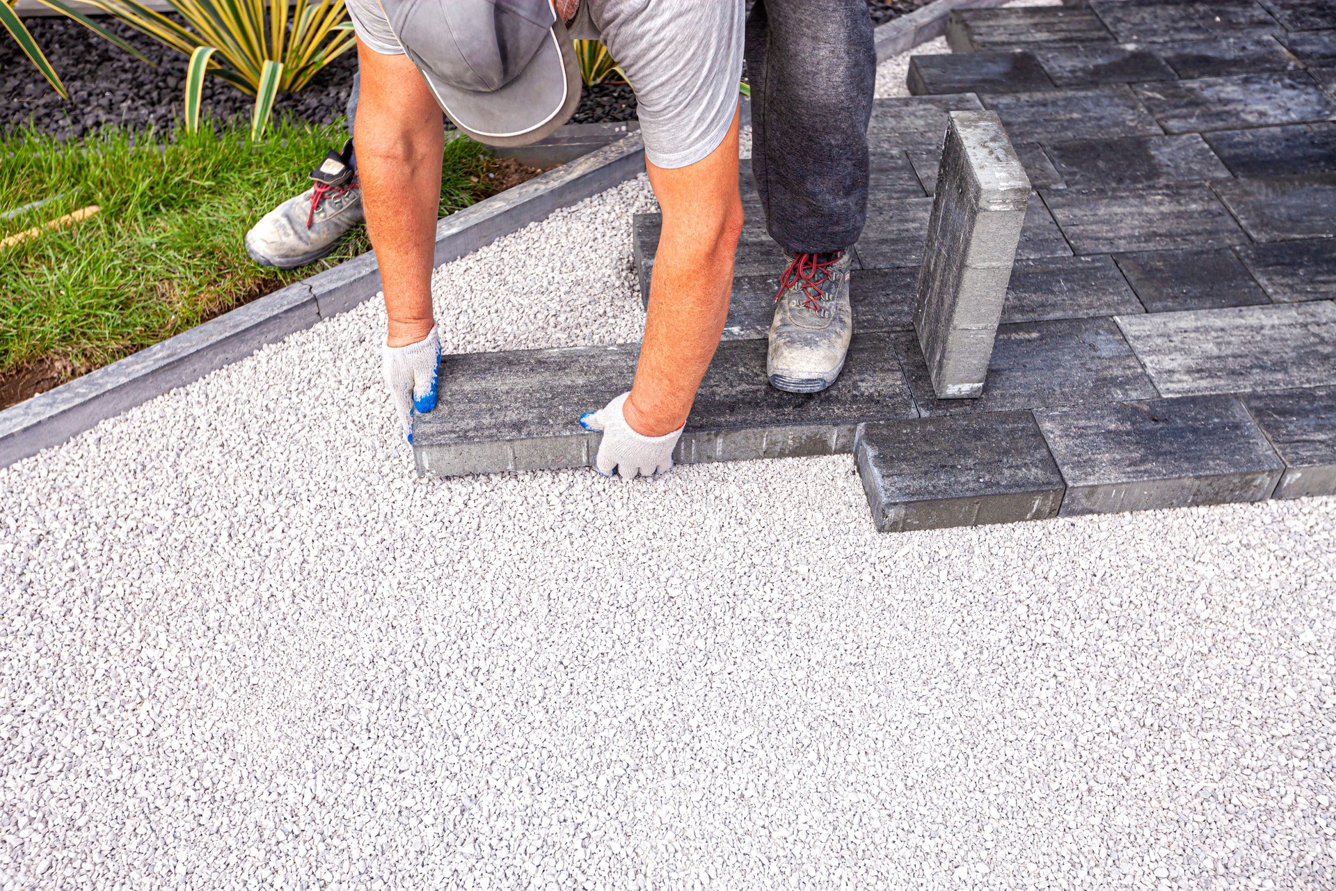 Professional interlock patio installation by Rejuvenation Renovations. A skilled contractor is carefully laying dark gray concrete pavers over a leveled gravel base, ensuring precision alignment and durability. The photo captures expert craftsmanship and attention to detail, showcasing the high-quality materials and techniques used in professional hardscaping and patio construction in Ottawa. Rejuvenation Renovations delivers expert interlock installation and hardscaping services across Ottawa. This project highlights our precision workmanship — from the gravel foundation to the final paver placement — ensuring long-lasting, beautiful patios and walkways. Trust our team for professional-grade outdoor transformations that combine strength, style, and function.